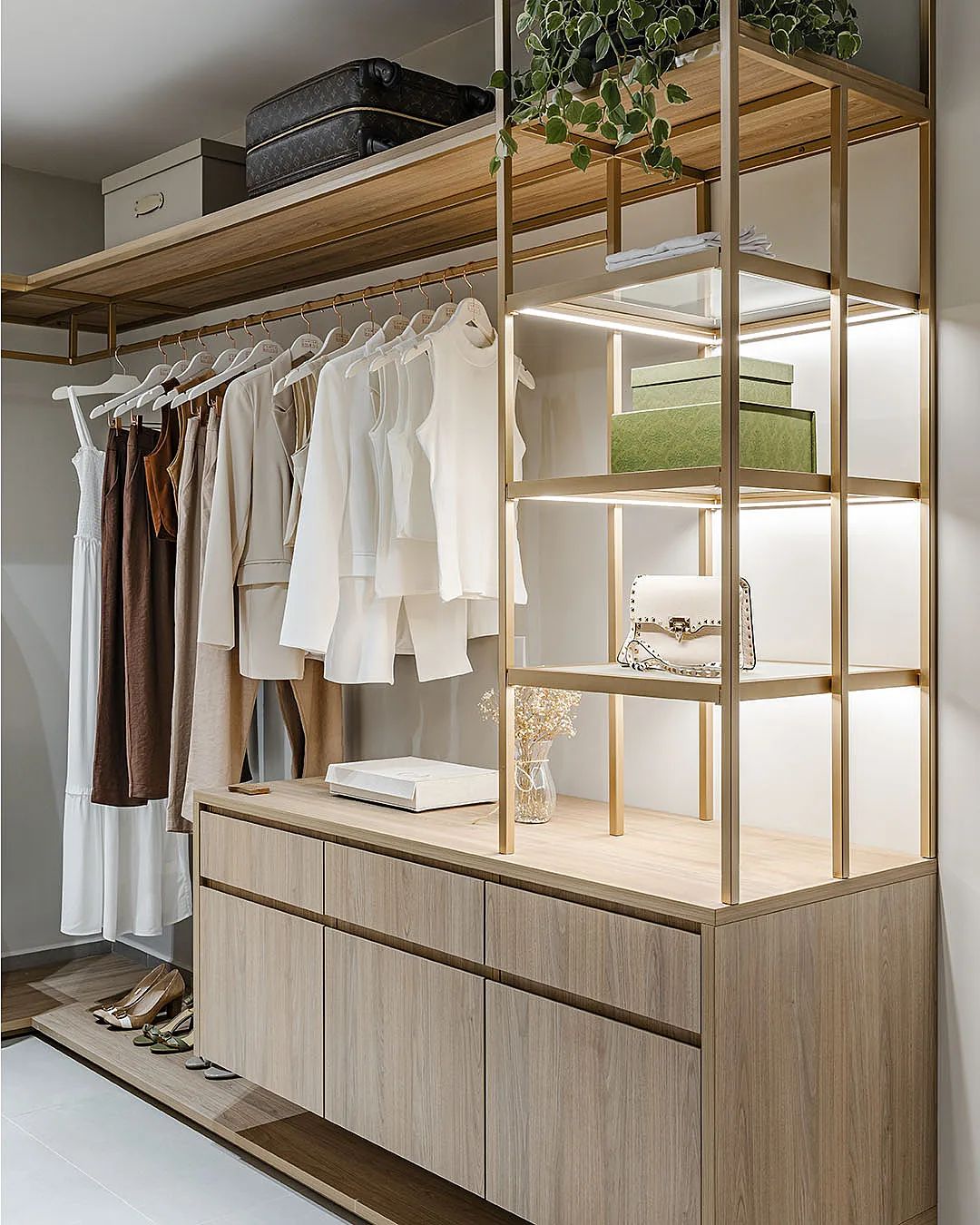 Closet planejado com estrutura metálica dourada e iluminação